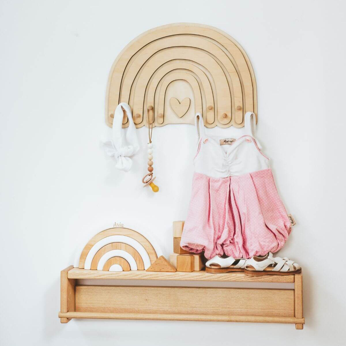 Natural wood rainbow wall hanger with pastel colors in a minimalist nursery setting