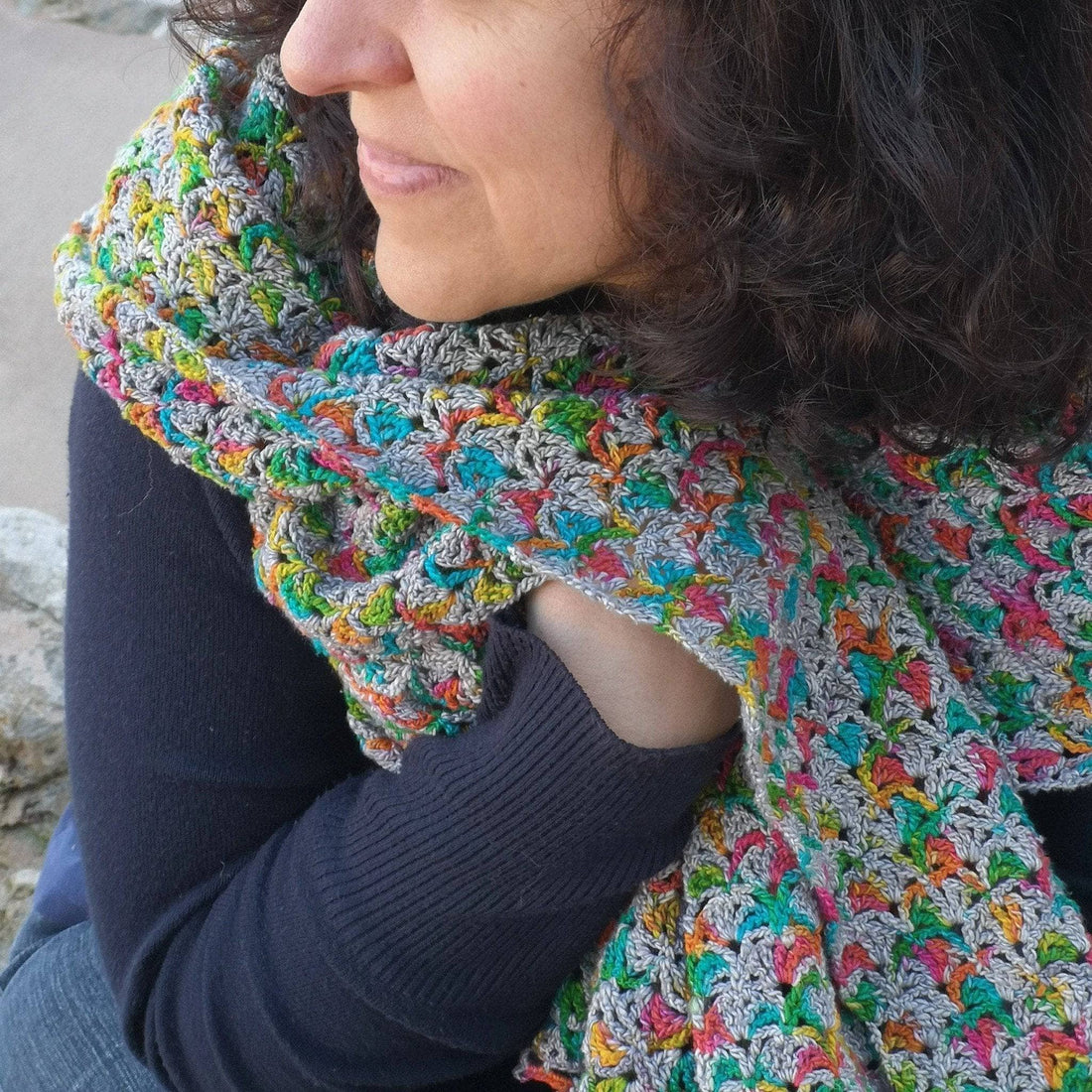 Gleeful Hummingbirds Wrap in grey and multi-color yarn displayed as a finished crochet accessory.