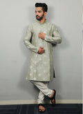 Men wearing a Pista green silk kurta with intricate copper sequence work detailing