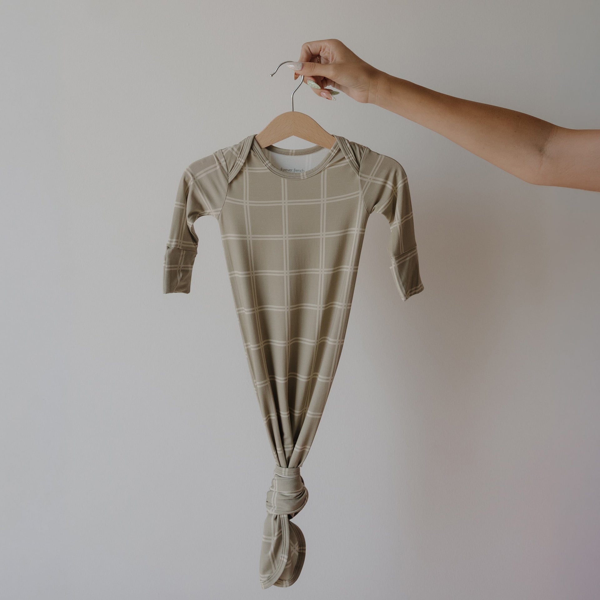 Newborn wearing a minimalist Linen Grid print bamboo knotted gown in a relaxed shift silhouette