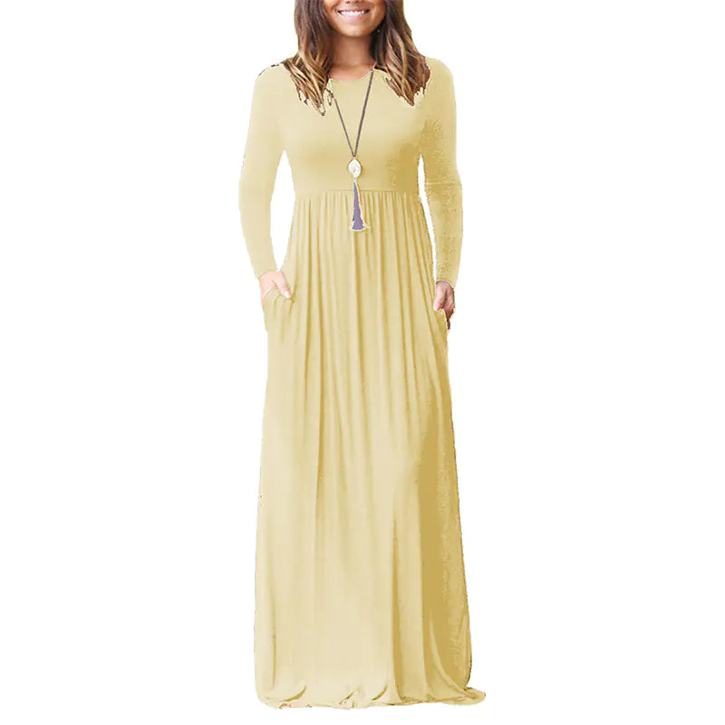 A woman wearing a solid color long-sleeve maxi dress with an elastic waist and side pockets.