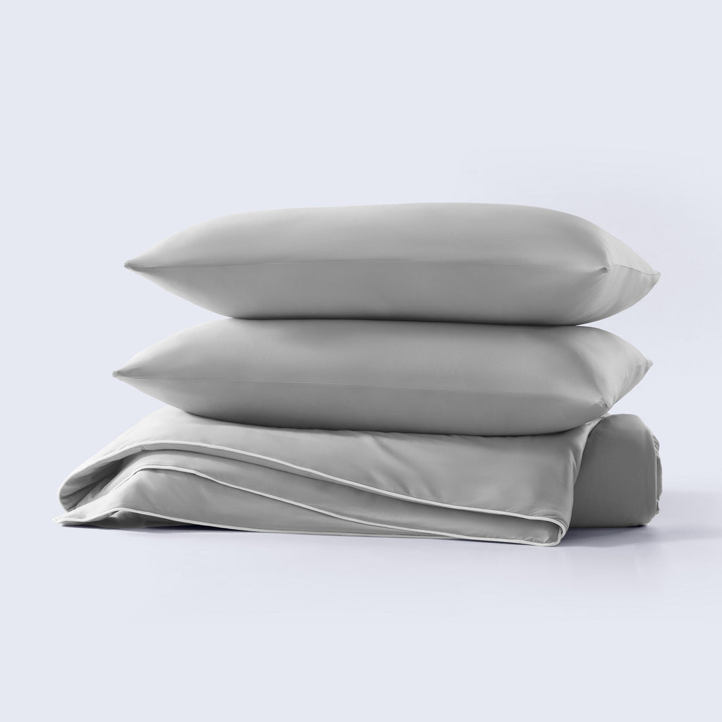A grey cooling comforter set with matching pillow shams shown on a made bed.