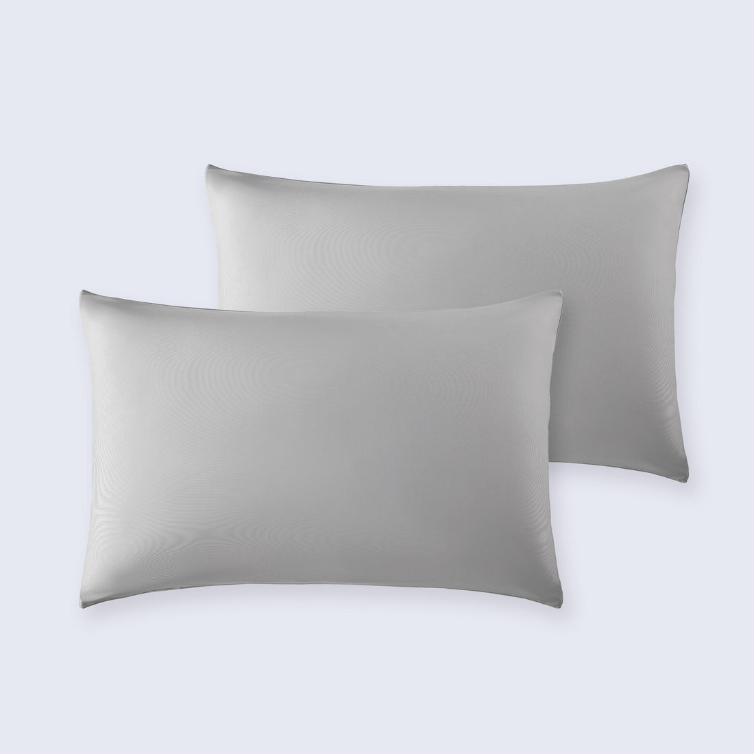 A pair of smooth, light gray cooling pillowcases displayed on a clean white bedding surface.