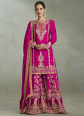 A woman wearing a rani pink chinon designer palazzo suit with intricate gota patti embroidery.