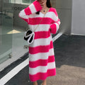 A woman wearing a long, fuzzy striped knitted pullover dress in pink and white, paired with a shoulder bag.