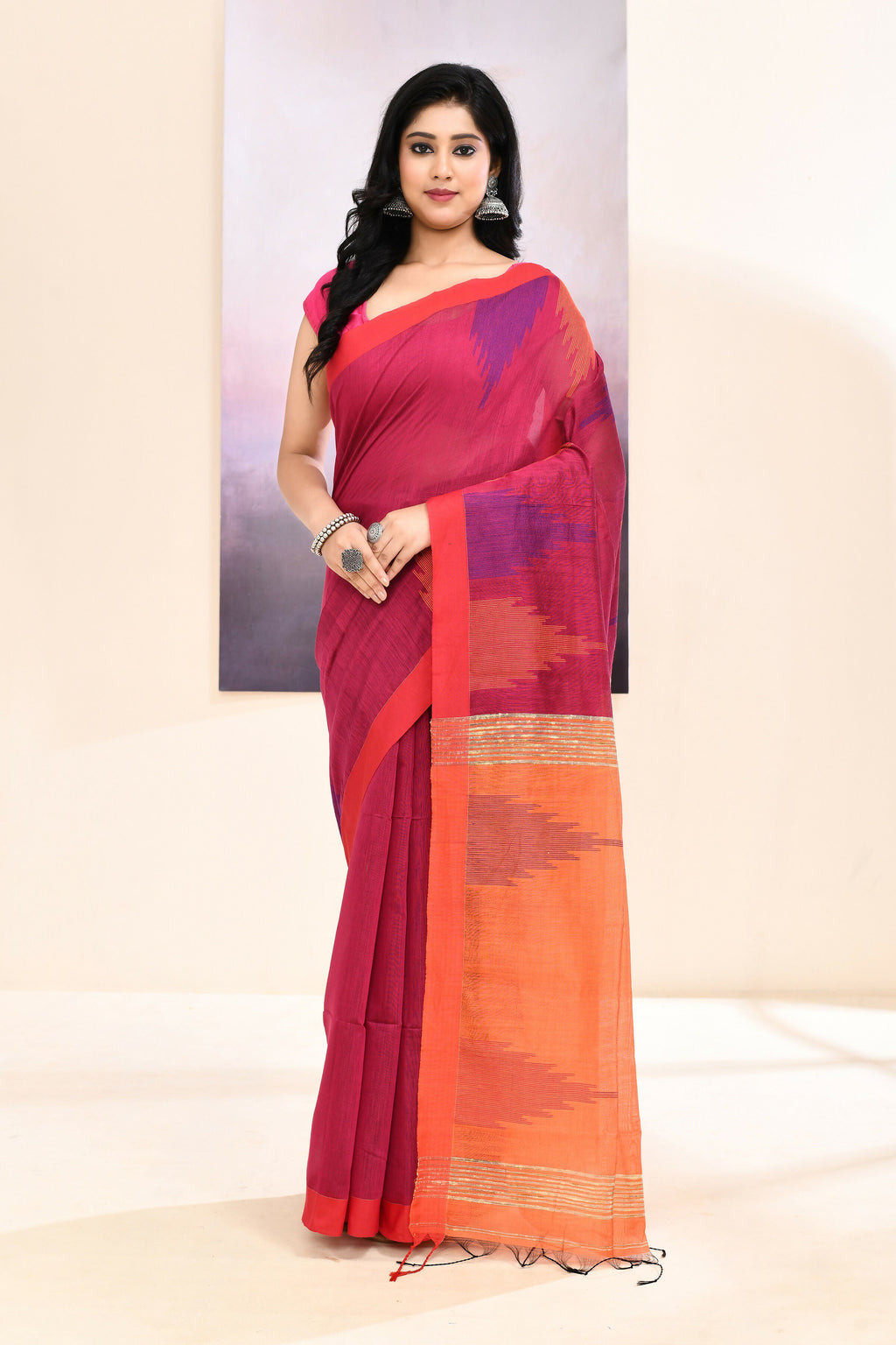 Rani colored cotton blend Jamdani saree with intricate gold temple border embellishment.