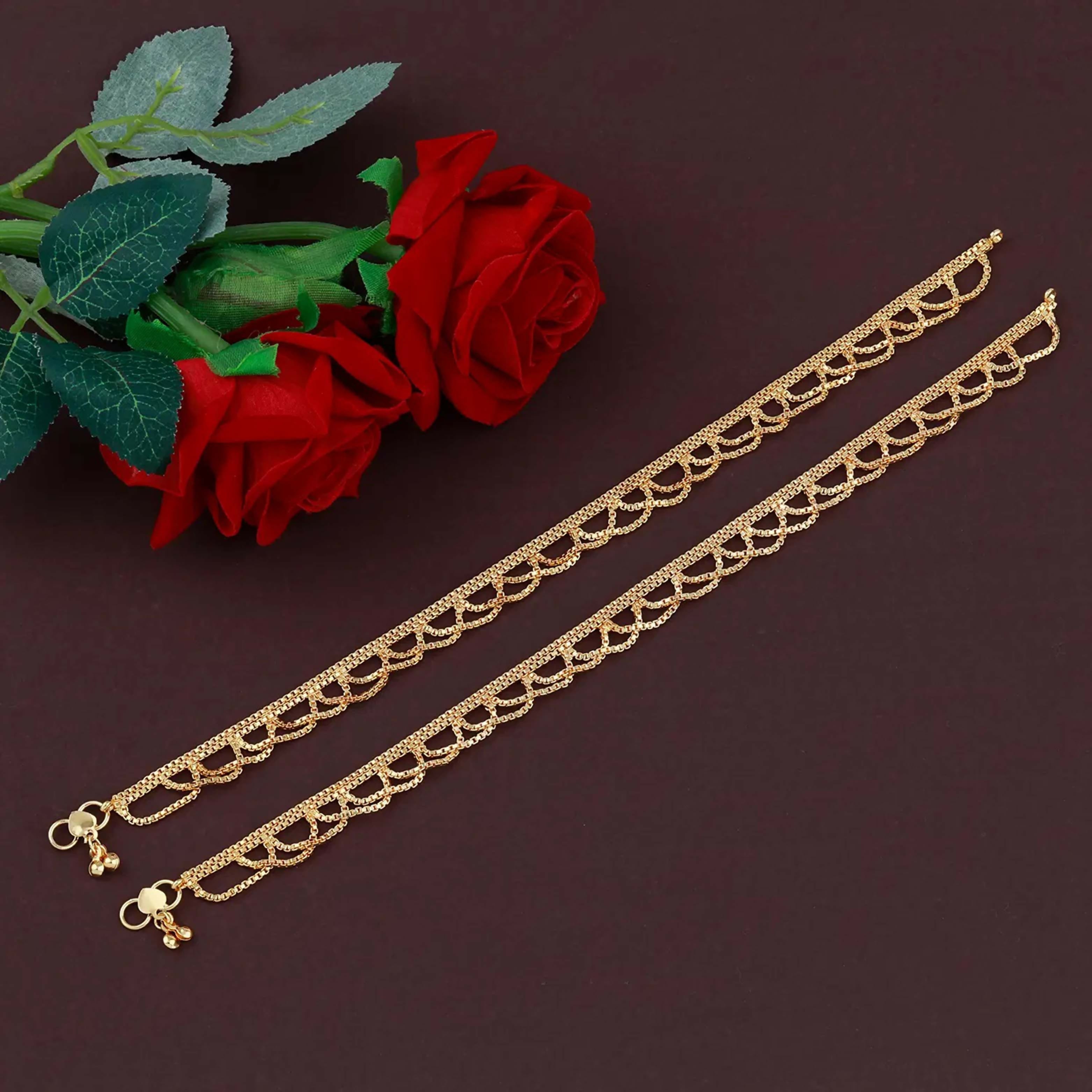 A pair of traditional golden copper anklets with a polished finish and hook closure