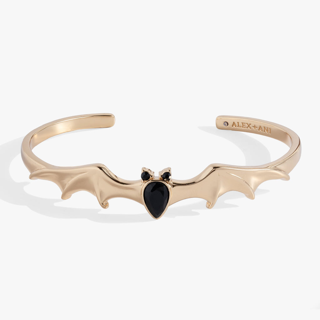 Gold cuff bracelet featuring a black crystal bat motif worn on a woman's wrist