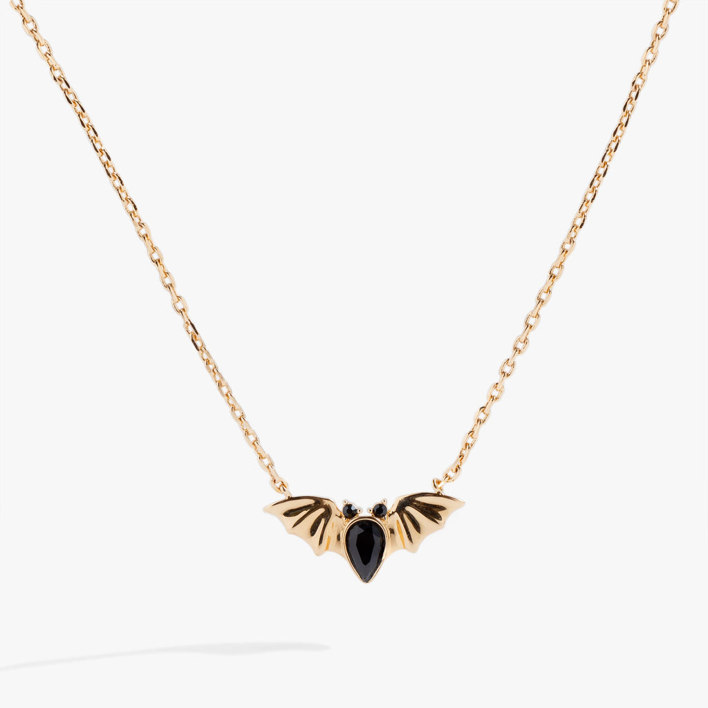 Close up of a silver bat-shaped pendant featuring three black pear-cut crystals on a silver cable chain.