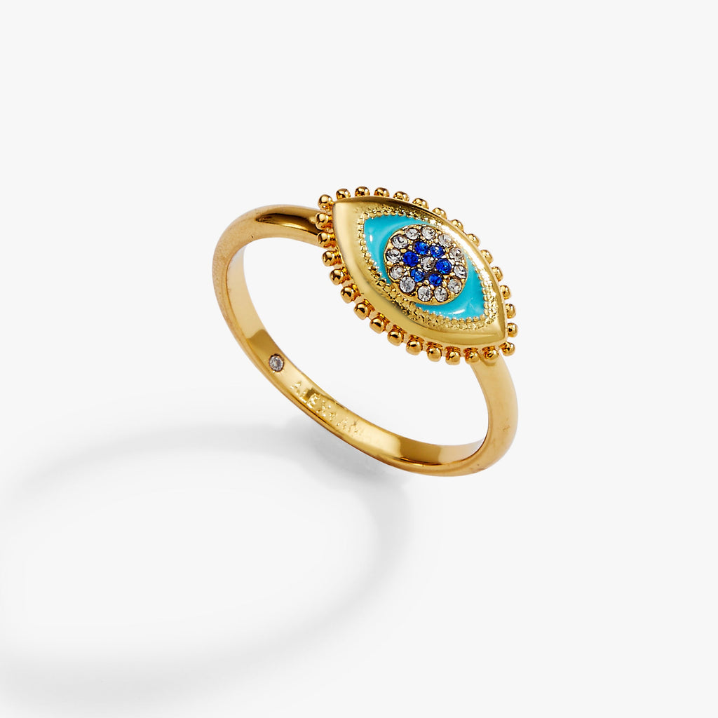 Close-up view of a delicate Evil Eye ring with enamel detailing and sapphire accents on a finger