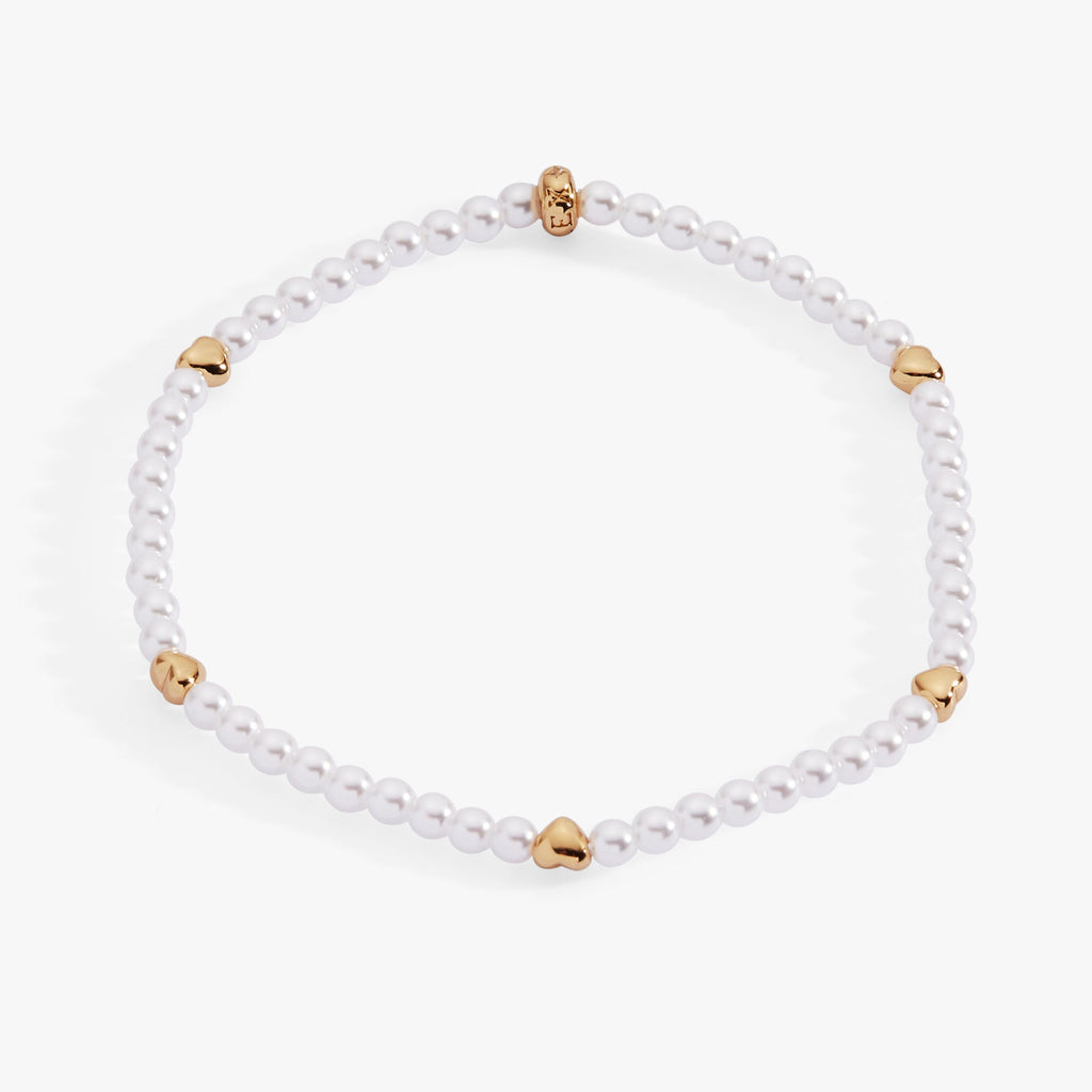 Elegant stretch bracelet featuring white faux pearls and gold-plated puffy hearts.