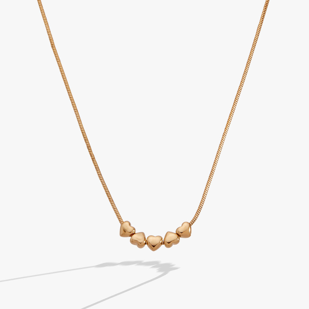Heart slider necklace featuring five gold-plated hearts on a silky snake chain.