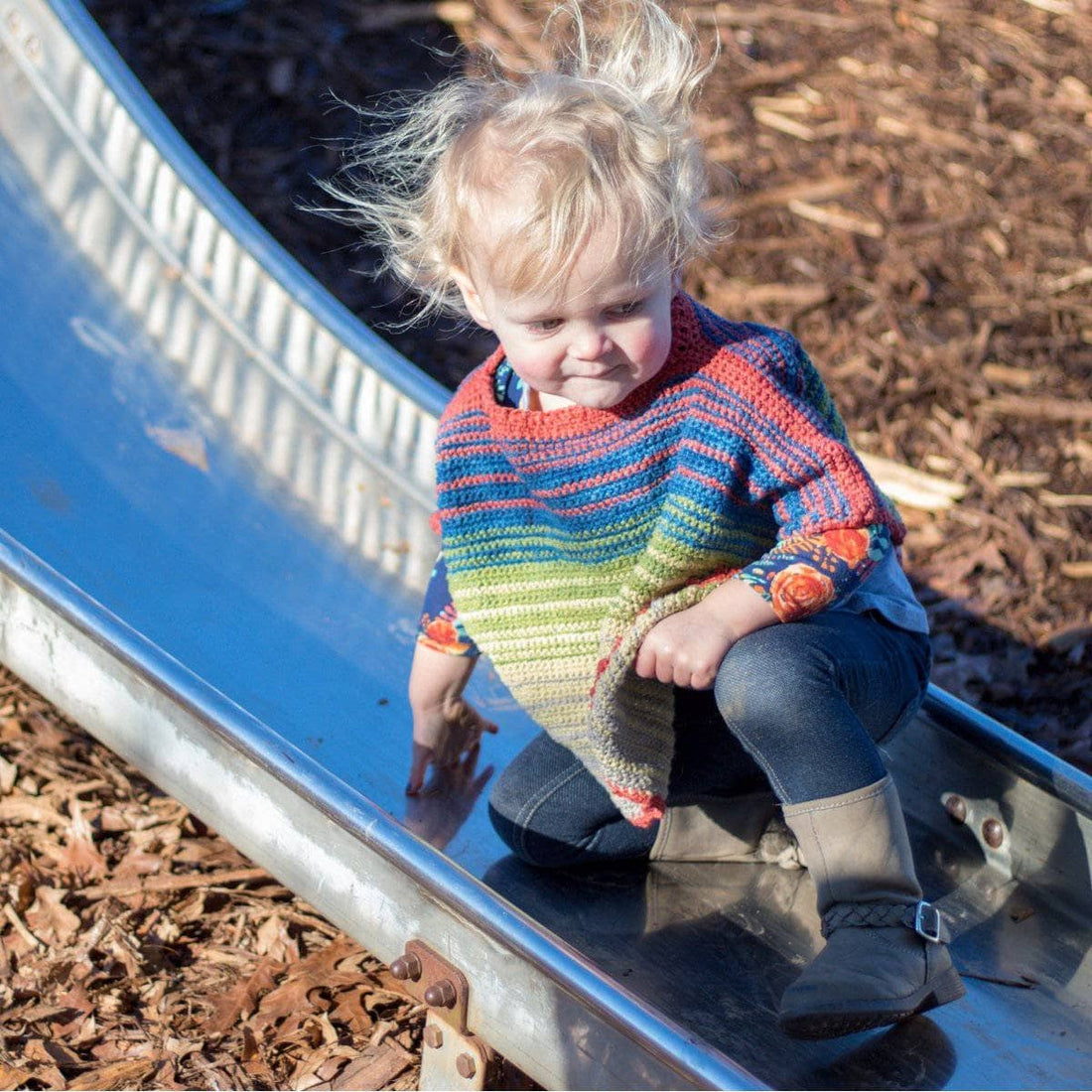 A toddler wearing a soft, herbal-dyed silk poncho made from a crochet pattern.