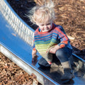 A toddler wearing a soft, herbal-dyed silk poncho made from a crochet pattern.