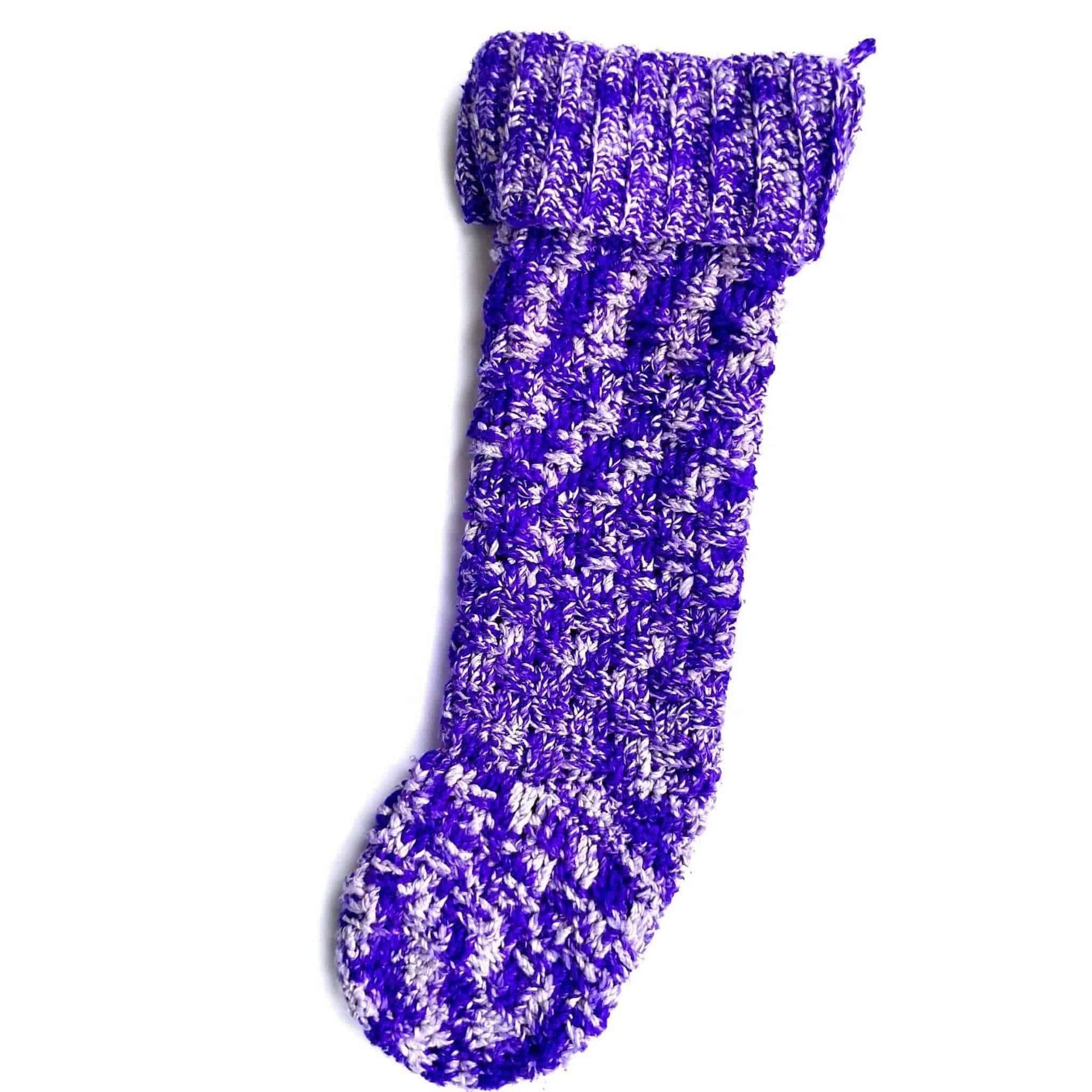 Handmade crochet Christmas stocking in variegated purple and white yarn displayed in a traditional living room.