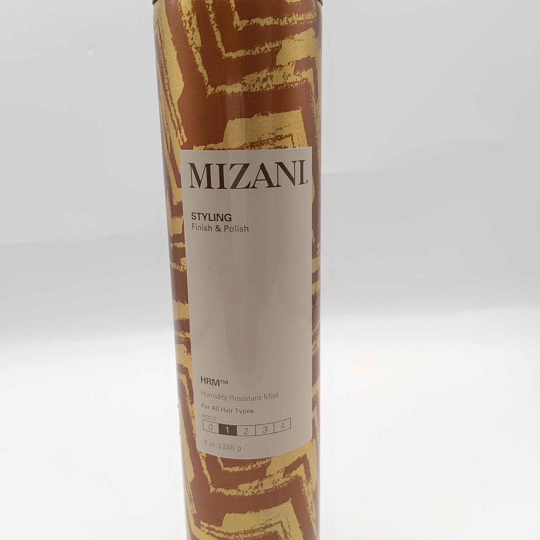 Mizani Humidity Resistant Mist bottle with metallic gold abstract brush strokes on a dark brown background.