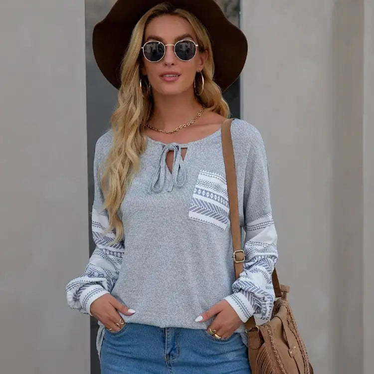 Model wearing a bohemian-style long sleeve top with a printed pattern, chest pocket, and tie-neck detail.