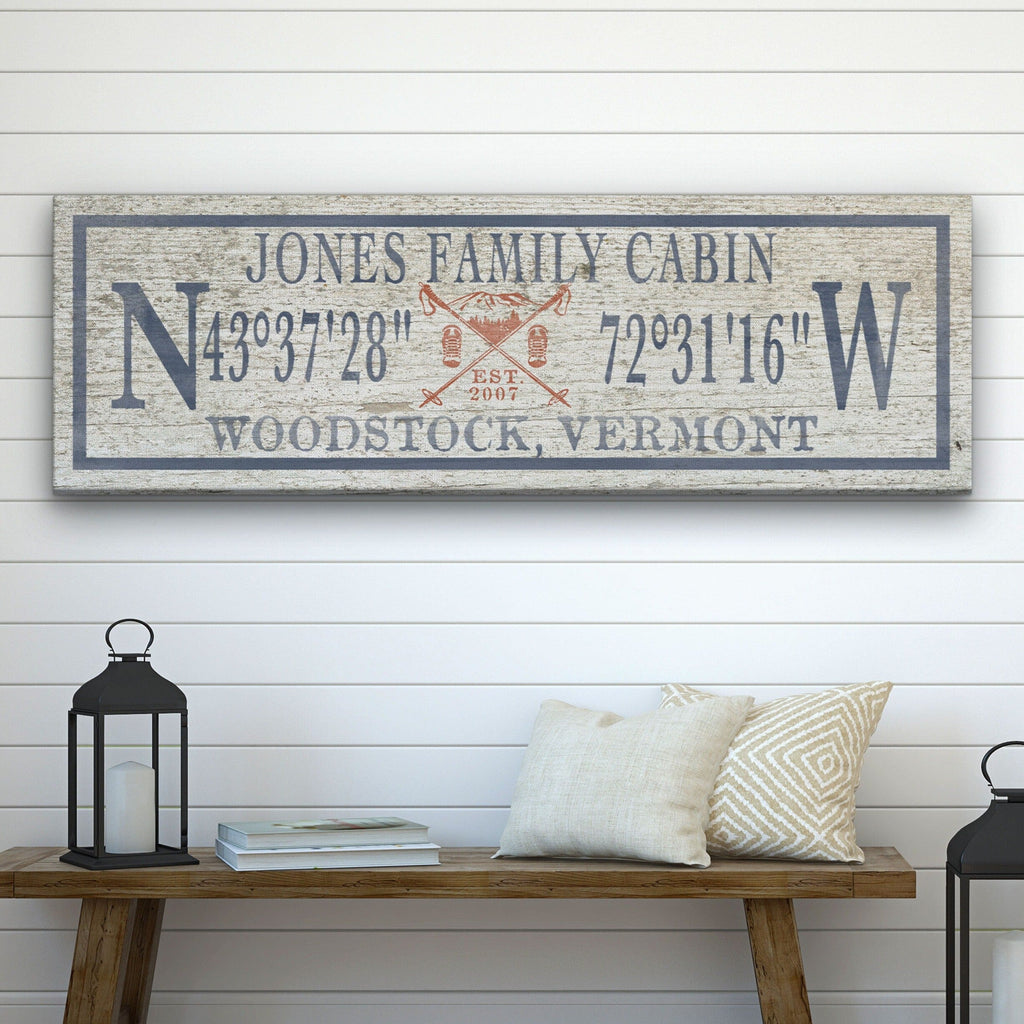 Personalized canvas sign for a ski lodge featuring a mountain icon and family name with coordinates.