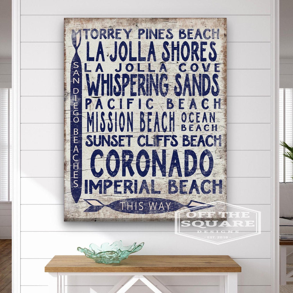 Vintage wood-look San Diego Beaches arrow sign with white-wash background and navy blue text