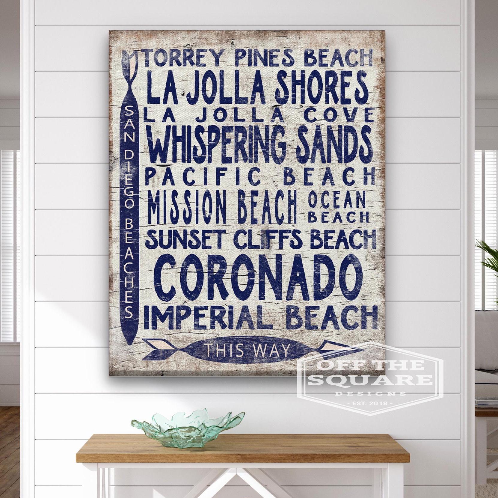 Vintage wood-look San Diego Beaches arrow sign with white-wash background and navy blue text
