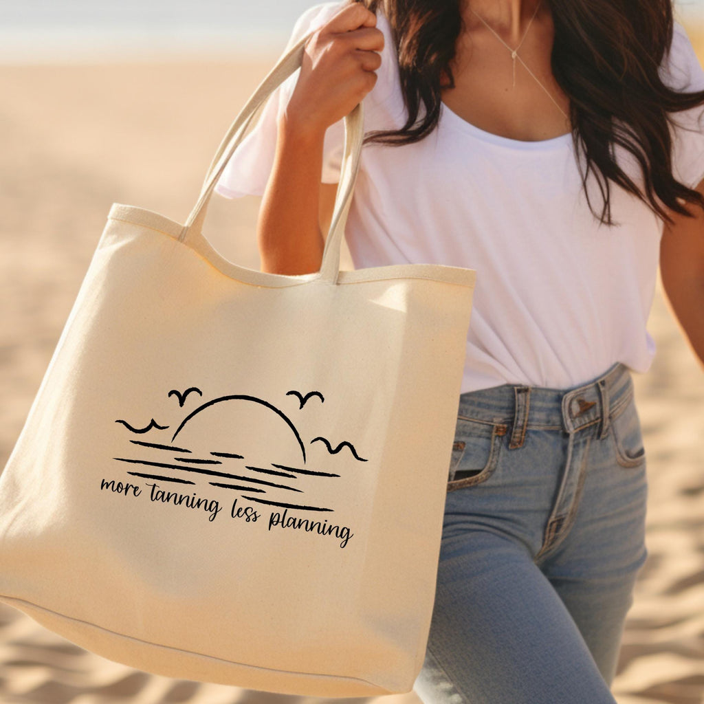 Person holding a tote bag with a beach design and text on a sandy background