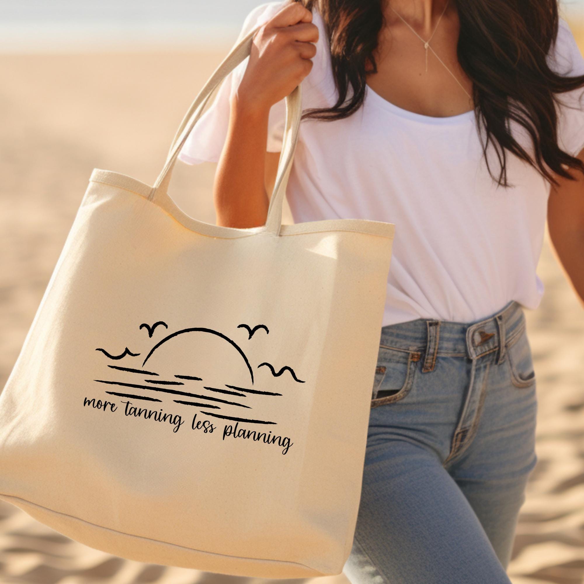 Person holding a tote bag with a beach design and text on a sandy background