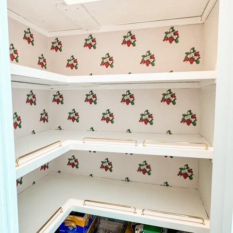 Gemma floral wallpaper featuring a cream base with strawberry red flowers and green foliage in a cottagecore style bedroom.