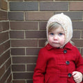 Close up of a soft merino wool baby hood in a beige knit texture.