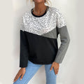 Woman wearing a color-block leopard print long-sleeve sweatshirt with grey and black panels.