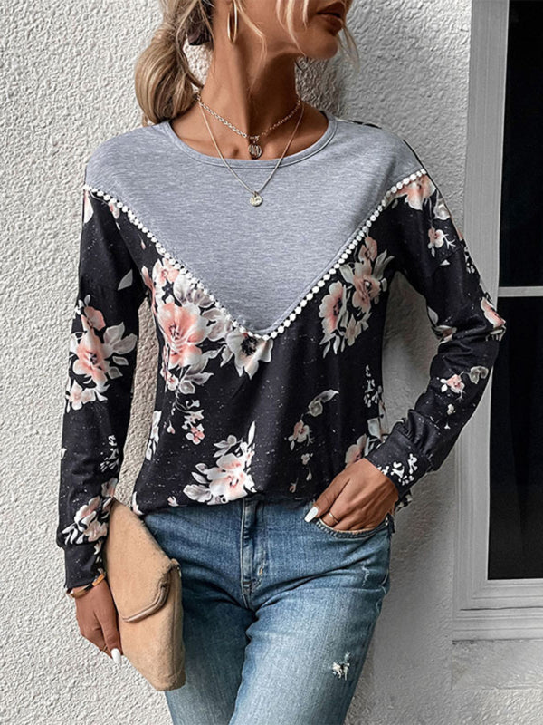 Woman wearing a long-sleeved color block top with grey bodice and black floral sleeves and lower body.