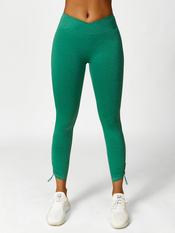 A pair of solid green high-rise yoga leggings with adjustable drawstring ankles on a model.