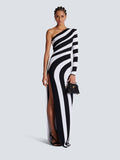 A full length view of a woman wearing a black and white zebra print one-shoulder long sleeve bandage maxi dress with a high side slit.