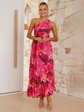 A woman wearing a vibrant pink floral one-shoulder pleated midi dress with a side hollow detail.