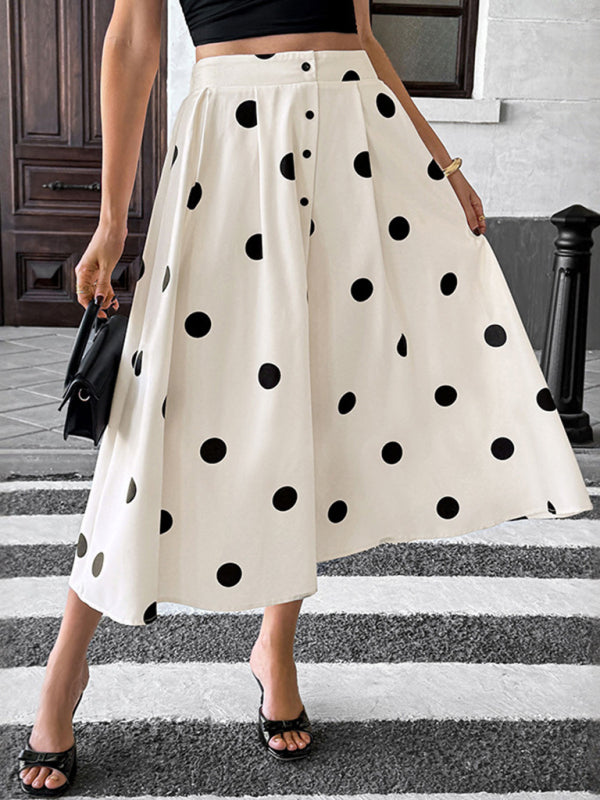 A woman wearing a white A-line midi skirt with a black polka dot pattern and front buttons, styled with a black top.