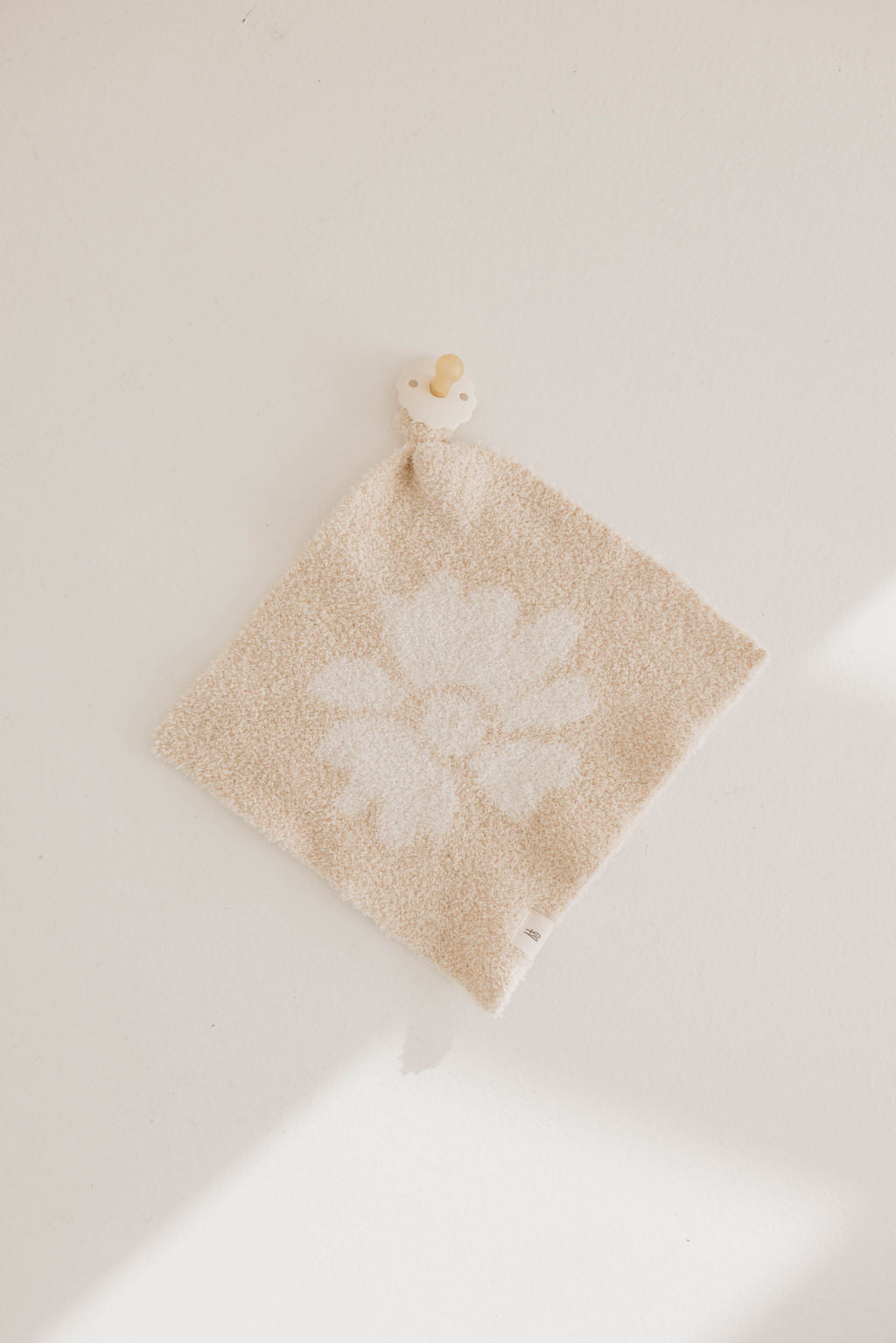 Lazy Daisy lovey featuring a soft floral knit pattern in neutral beige and cream colors.