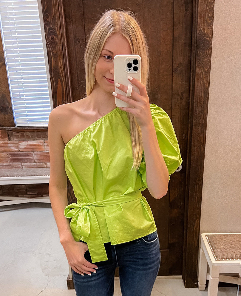 Front view of a 100% cotton one-shoulder blouse featuring a dramatic puff sleeve and lace-up detailing.