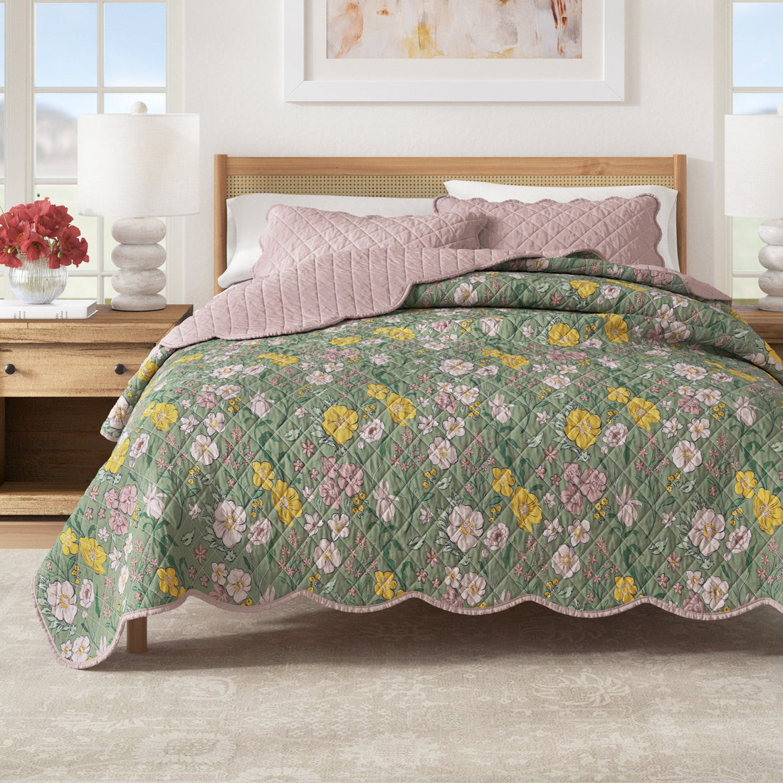 Floral print quilt with scalloped edges and a reversible solid pink side on a bed