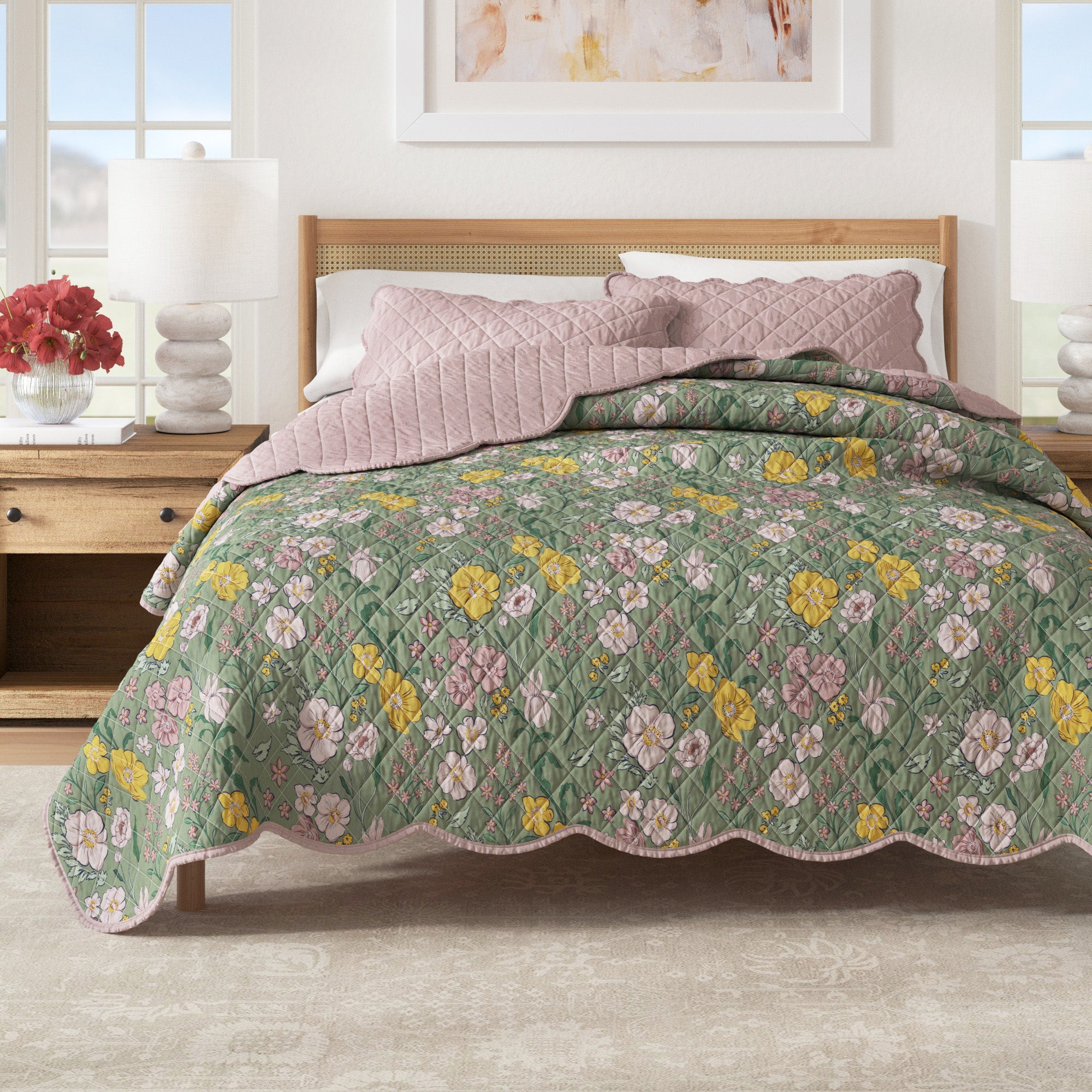 Floral print quilt with scalloped edges and a reversible solid pink side on a bed