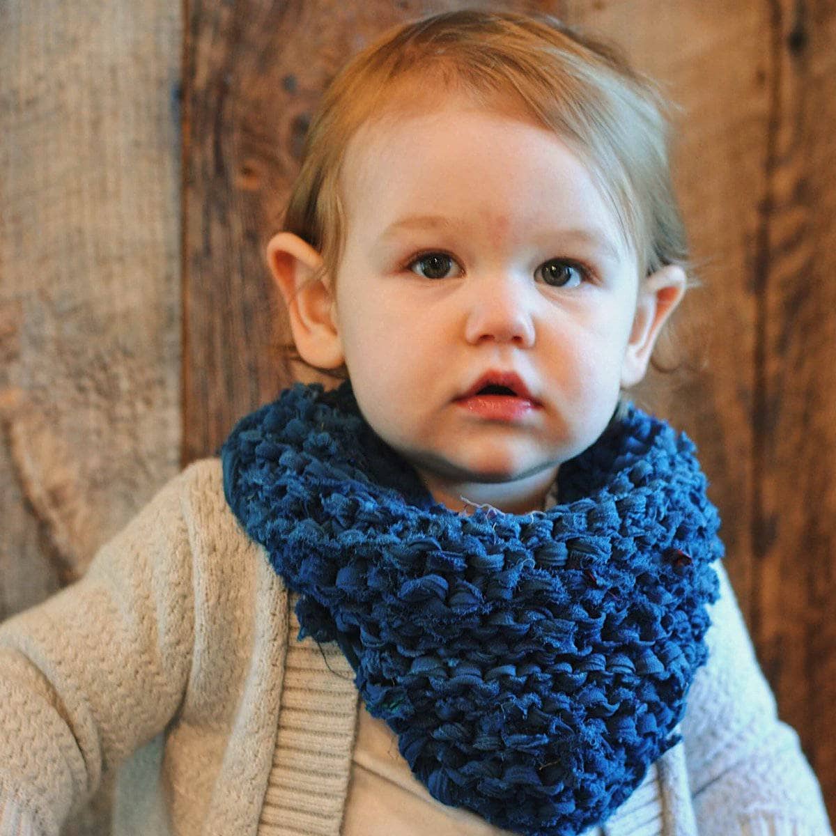 A close-up of a hand-knitted kerchief made with ribbon yarn.