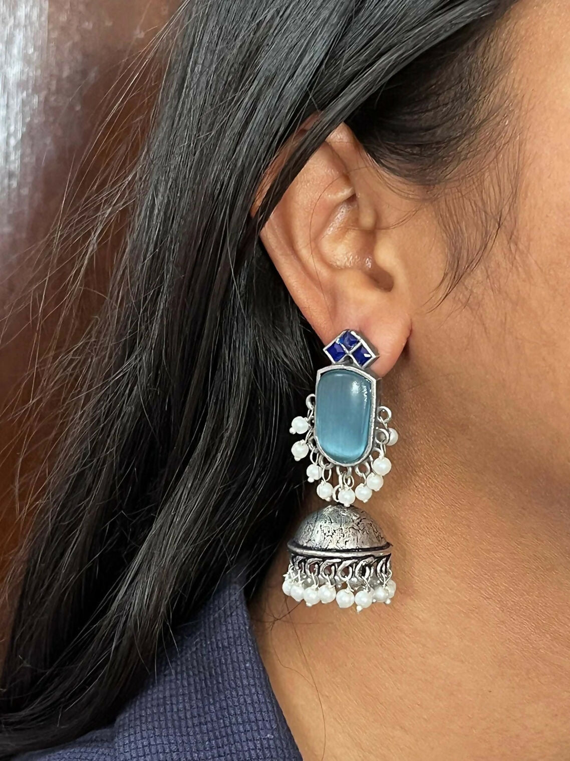 Close-up of blue Monalisa stone zigzag earrings with golden brass finish