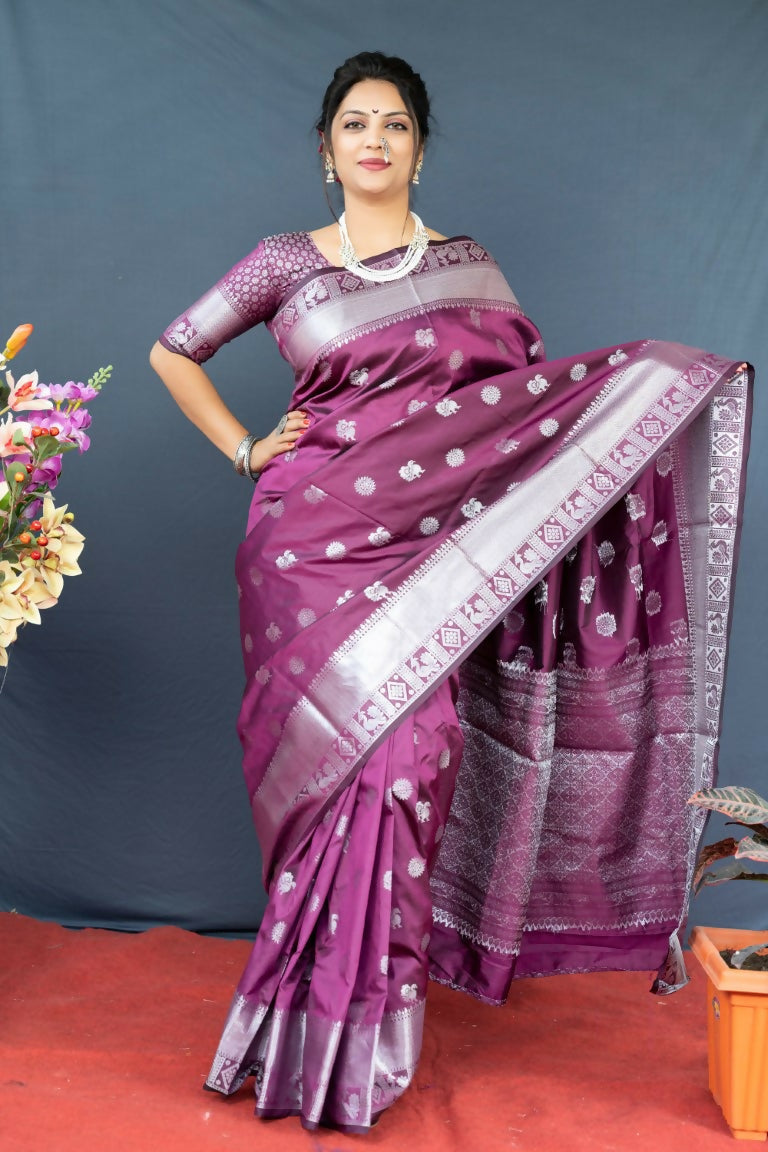Woman wearing a wine-colored soft Banarasi silk saree with gold Zari woven borders and matching blouse.