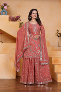 A woman wearing a pink georgette embroidered kurti with matching flared sharara pants.