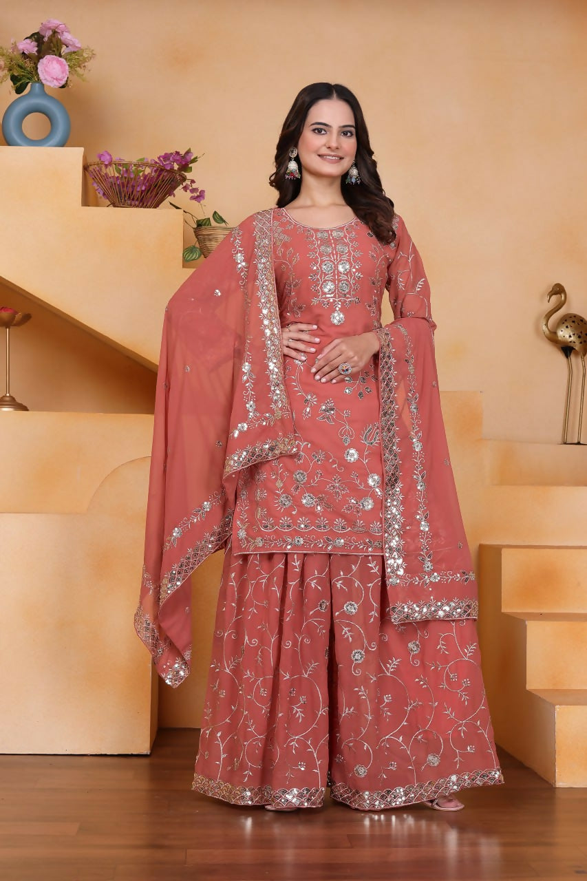 A woman wearing a pink georgette embroidered kurti with matching flared sharara pants.