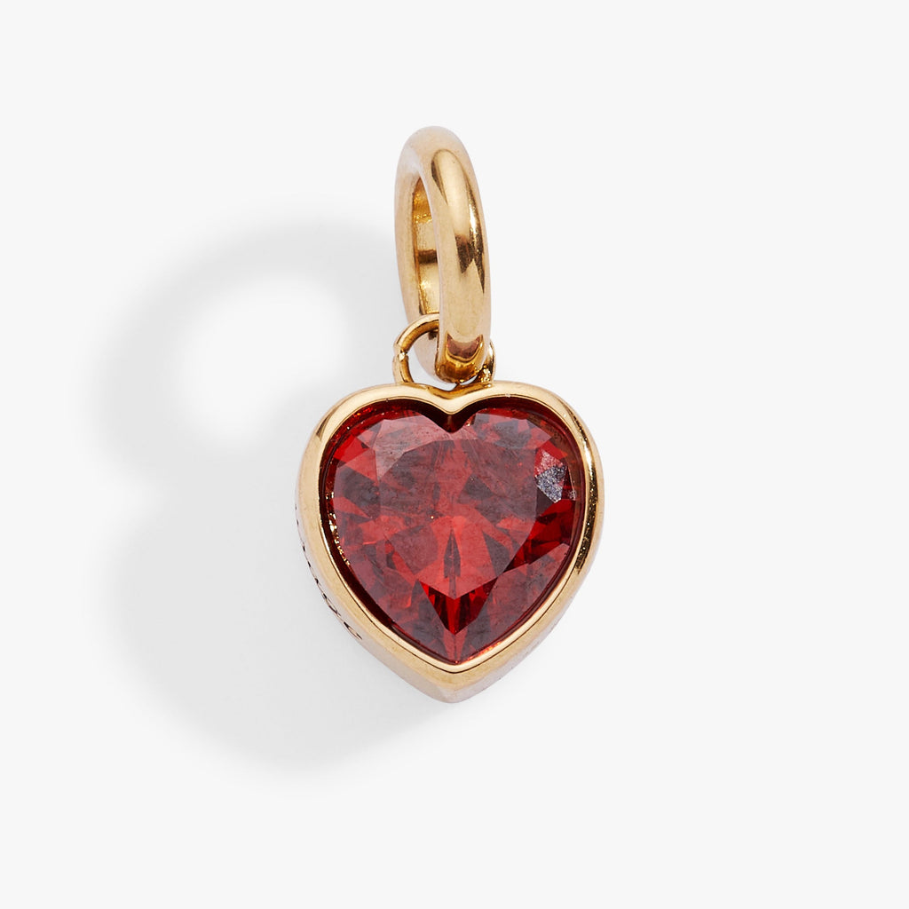 Close up of a faceted garnet-colored heart charm with the word Courage etched on the side