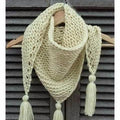 Close up of a hand-knitted triangle scarf featuring trendy tassels and textured stitches