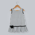 Girl's sleeveless black and white box print A-line dress with a black taffeta bow at the hem.