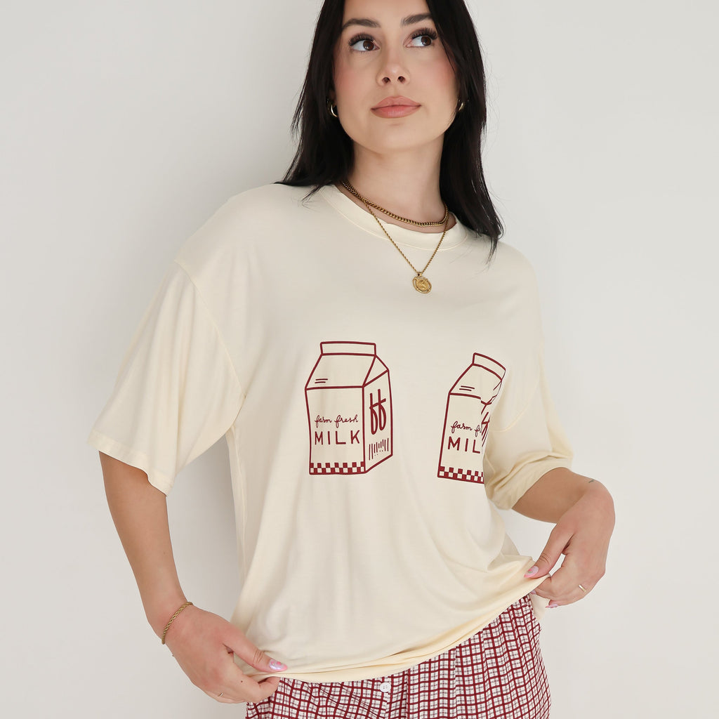 Model wearing a cream oversized t-shirt with milk carton graphic and window pane patterned lounge pants