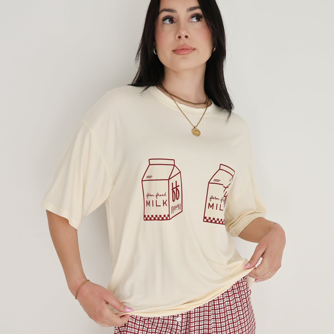 Model wearing a cream oversized t-shirt with milk carton graphic and window pane patterned lounge pants