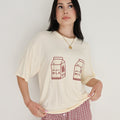 Model wearing a cream oversized t-shirt with milk carton graphic and window pane patterned lounge pants