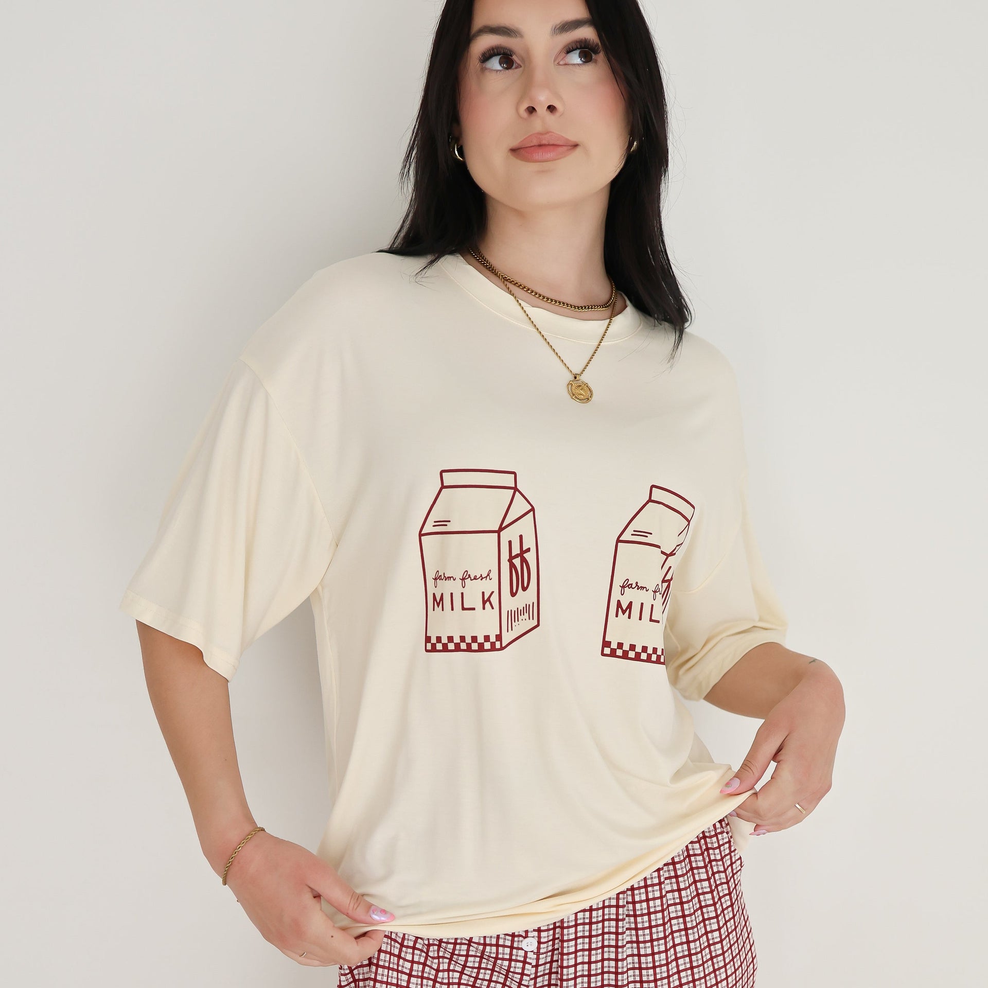 Model wearing a cream oversized t-shirt with milk carton graphic and window pane patterned lounge pants
